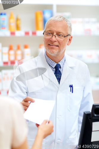 Image of senior apothecary with prescription at pharmacy