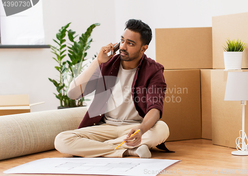 Image of man with blueprint and boxes moving to new home
