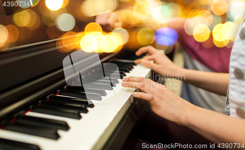 Image of close up of woman hands playing piano over lights