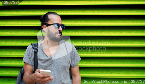 Image of man in sunglasses with smartphone and bag at wall