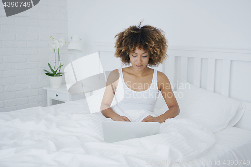 Image of Charming woman with laptop in bed