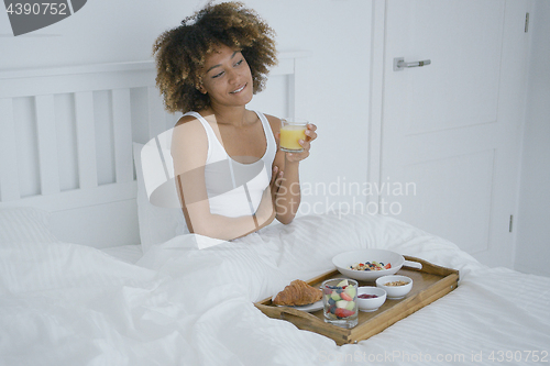Image of Content woman enjoying breakfast in bed