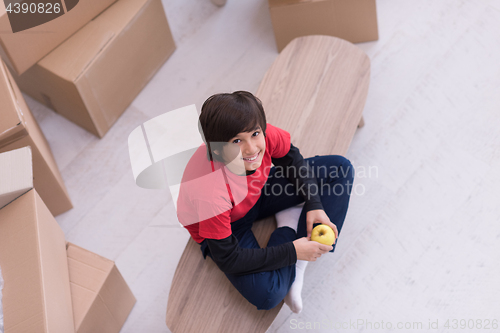 Image of boy sitting on the table with cardboard boxes around him top vie