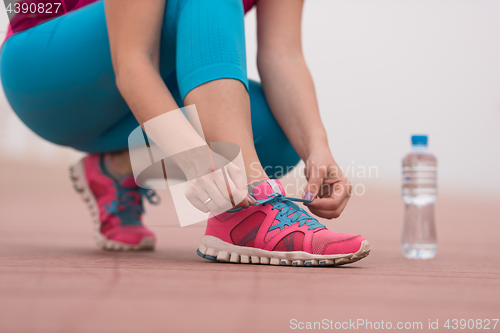 Image of Young woman tying shoelaces on sneakers