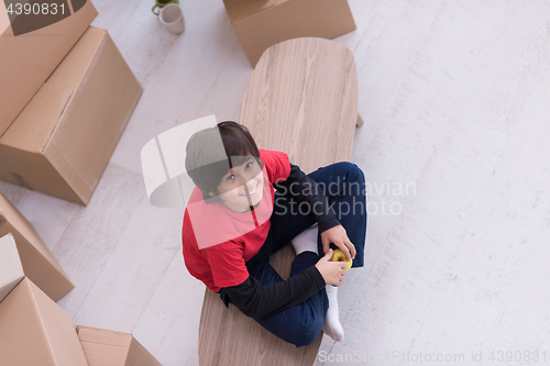 Image of boy sitting on the table with cardboard boxes around him top vie