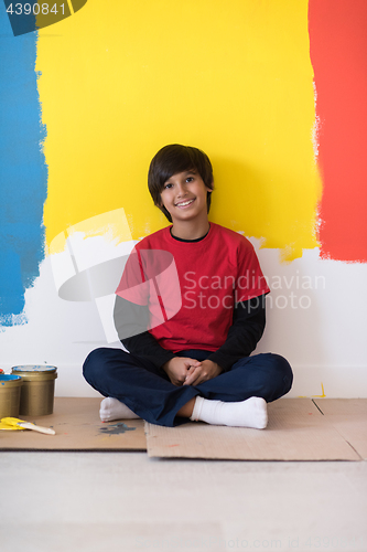 Image of young boy painter resting after painting the wall