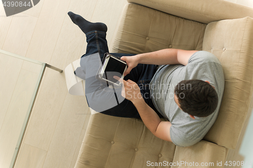 Image of man on sofa using tablet computer