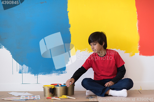 Image of young boy painter resting after painting the wall