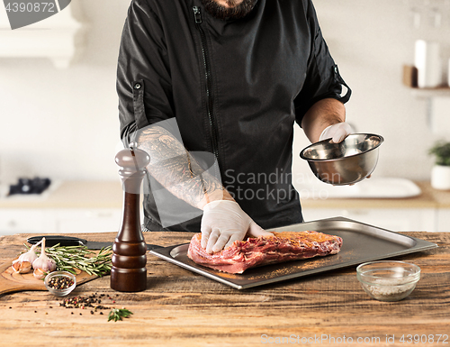 Image of Man cooking meat steak on kitchen