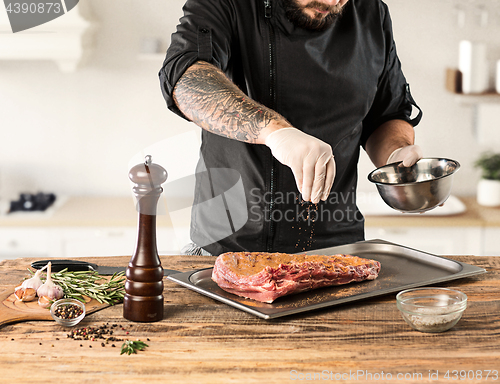 Image of Man cooking meat steak on kitchen