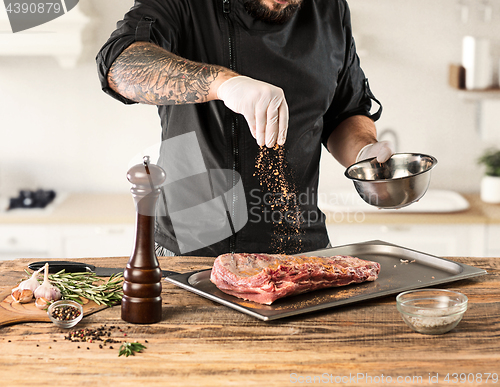 Image of Man cooking meat steak on kitchen