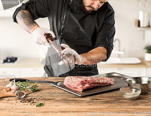 Image of Man cooking meat steak on kitchen