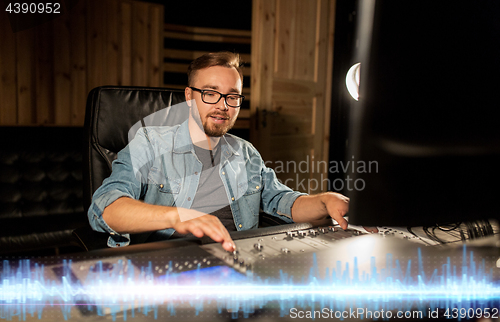 Image of sound engineer at recording studio mixing console