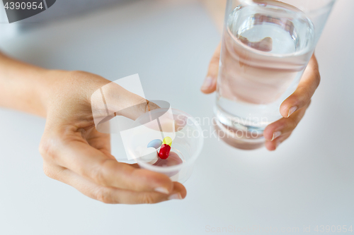 Image of close up of hands with pills and glass of water