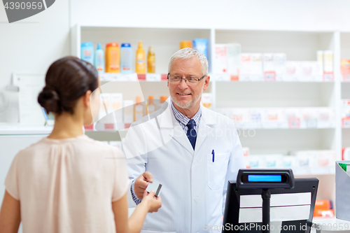 Image of apothecary taking customer credit card at pharmacy