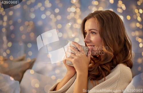 Image of happy woman with cup of coffee in bed at home