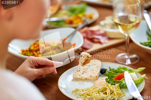 Image of hands of woman eating pasta with chicken