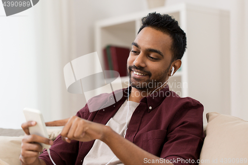 Image of man in earphones listening to music on smartphone