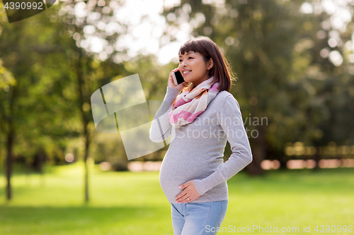 Image of pregnant asian woman calling on smartphone at park