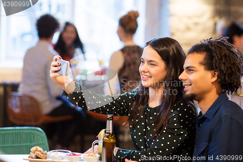 Image of happy couple taking selfie at restaurant or bar