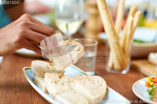 Image of hand taking piece of bread from plate