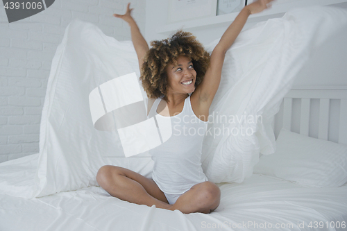 Image of Happy woman on bed with blanket