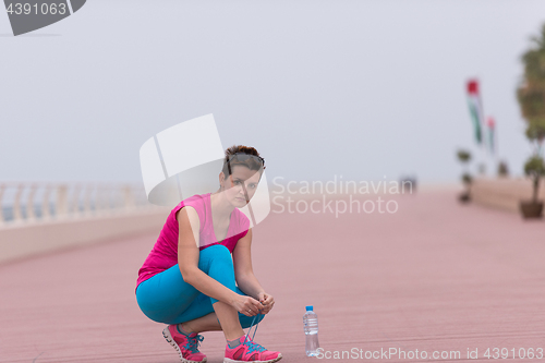 Image of Young woman tying shoelaces on sneakers