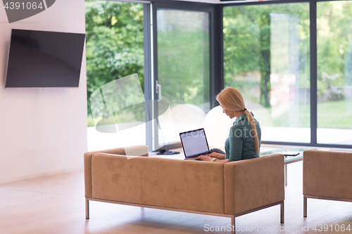 Image of Young woman using laptop at home