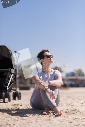 Image of Young mother with sunglasses relaxing on beach