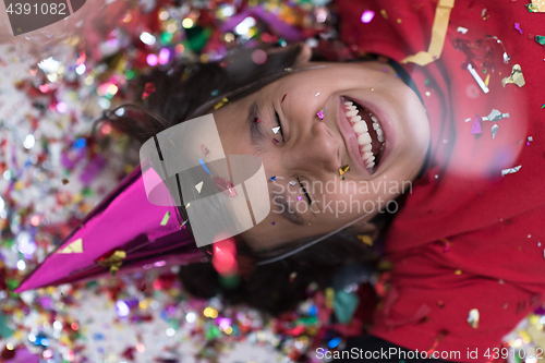 Image of kid blowing confetti while lying on the floor