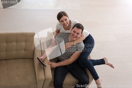 Image of couple relaxing at  home with tablet computers