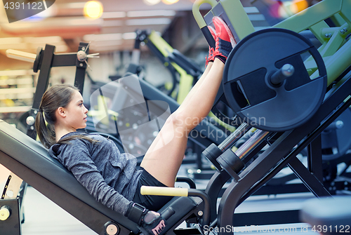 Image of woman flexing muscles on leg press machine in gym