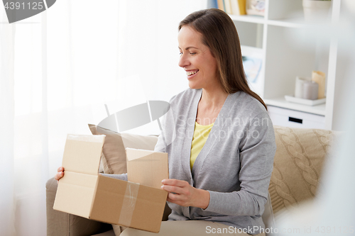 Image of smiling woman opening parcel box at home