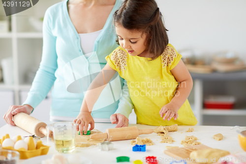 Image of happy mother and daughter making cookies at home