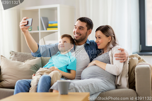 Image of happy family taking selfie with smartphone at home