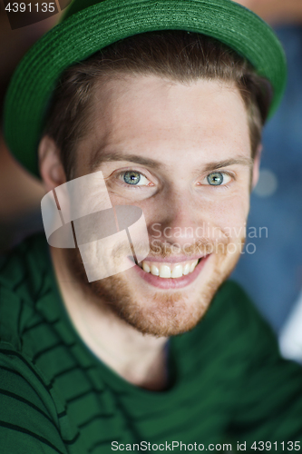 Image of portrait of happy young man in green hipster hat