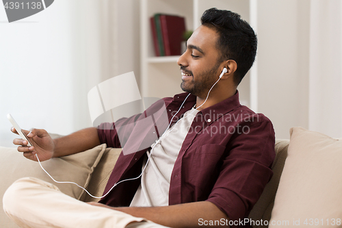 Image of man in earphones listening to music on smartphone