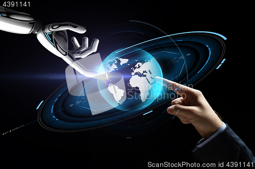 Image of human and robot hand with virtual earth hologram