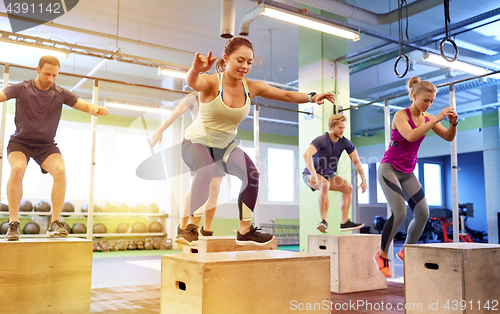 Image of group of people doing box jumps exercise in gym