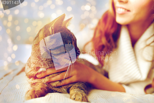 Image of happy young woman with cat lying in bed at home