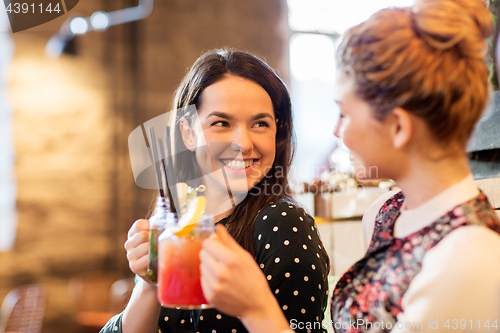 Image of happy friends clinking drinks at restaurant