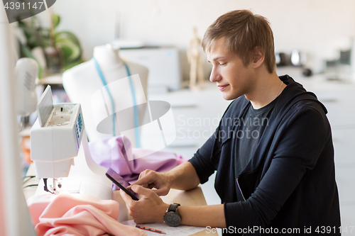 Image of fashion designer with tablet pc working at studio
