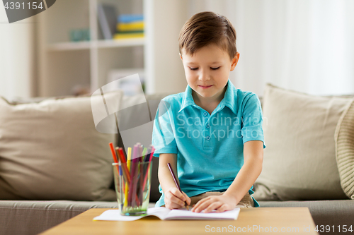 Image of boy with notebook and pencils drawing at home