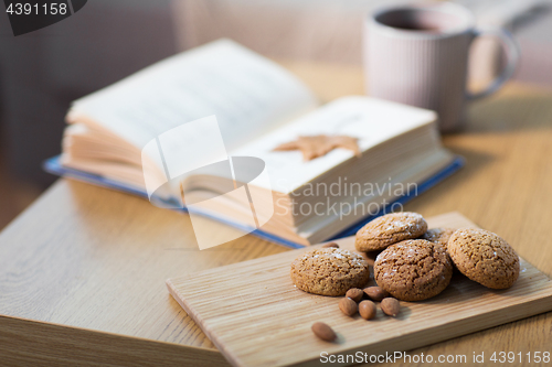 Image of oat cookies, almonds and book on table at home