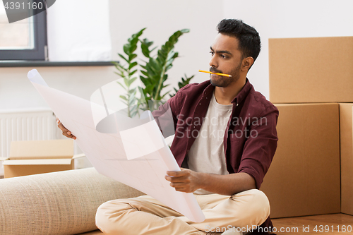 Image of man with blueprint and boxes moving to new home