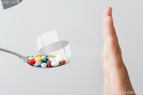 Image of close up of female hand holding spoon with pills