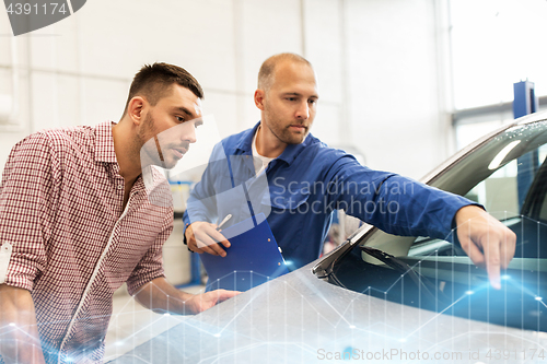 Image of auto mechanic with clipboard and man at car shop