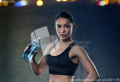 Image of woman drinking water from bottle in gym