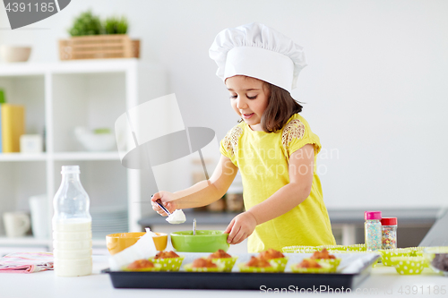 Image of little girl in chefs toque baking muffins at home