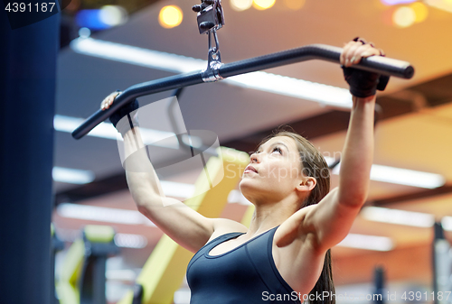 Image of woman flexing arm muscles on cable machine in gym